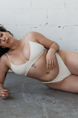 Woman laying on the ground wearing a white bikini with minimal coverage