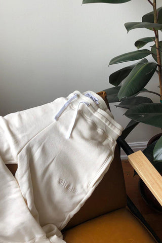 White oversized cotton joggers draped over a brown chair.